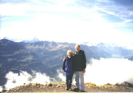 Photo of Fred and Kathy standing on the edge of the mountain with many mountains in the distance