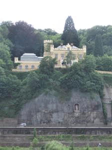 An estate atop a rock, with separately tiered car, train, and bicycle lanes below